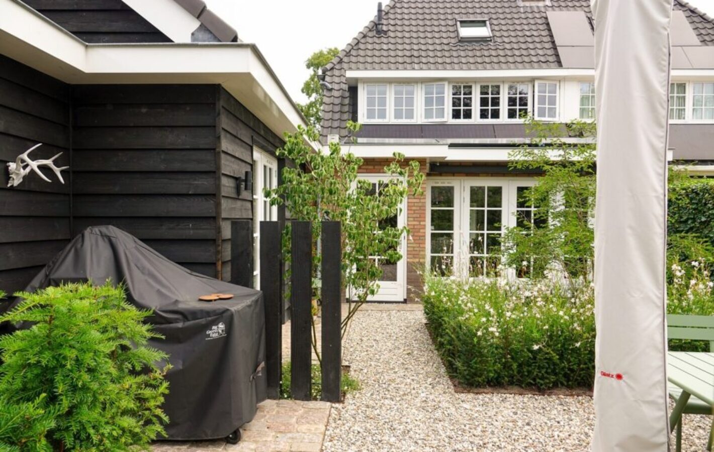 Strakke voor- en achtertuin met binnentuin, bij jaren '30 woning in Laren